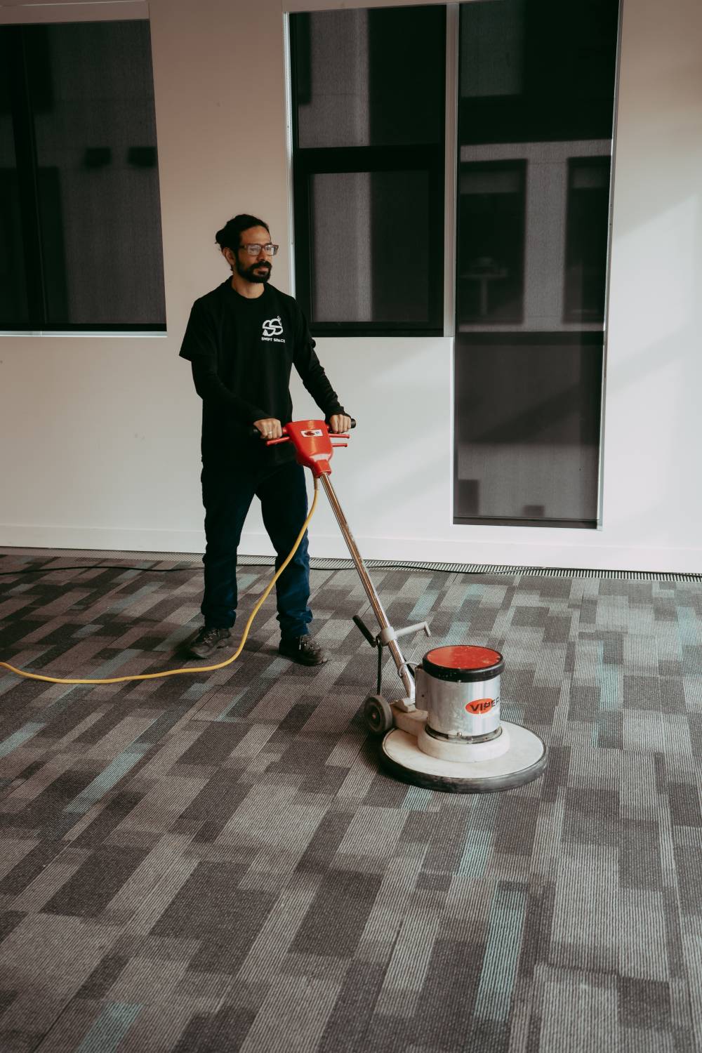 Man pushing floor buffer in office. 